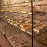 Una parte degli oggetti rinvenuti in queste sepolture e in quelle delle confraternite viste poco prima � conservata all�interno di apposite teche. Sono databili dal XII al XVI secolo: fibule, monete, piatti, lucerne